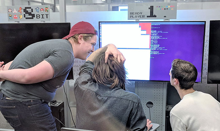 Students looking at a monitor while a program runs on the screen.