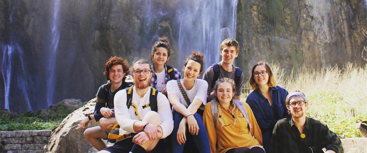 Students sit near a waterfall in the Alps