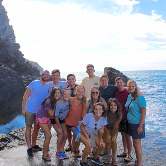 Study abroad students stand near the sea for a picture during an excursion.