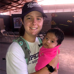 Softball student holds a infant on a mission trip to Baja, Mexico