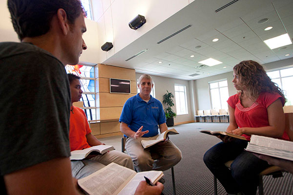 A professor leads students with their Bibles open in a discussion through Scripture