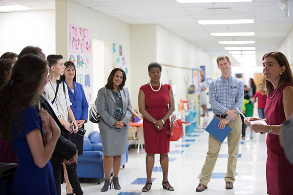An administrator talks to a group of teachers in a school hallway