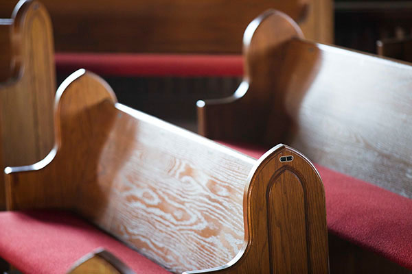Two wooden pews with red seat cushions