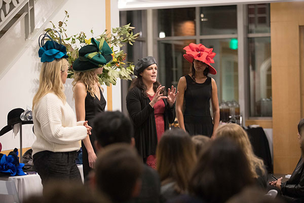A designer explains some of her hat designs at a fashion show