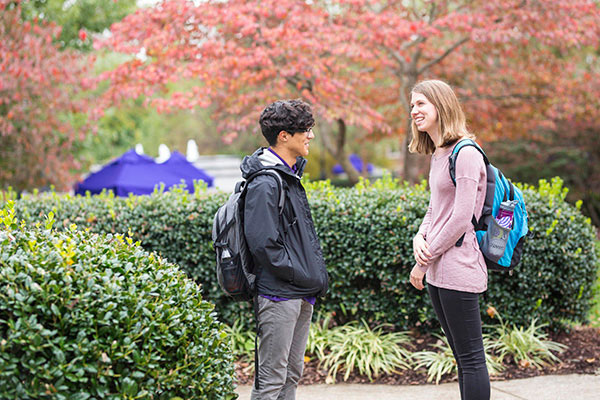 Two students stand outside talking