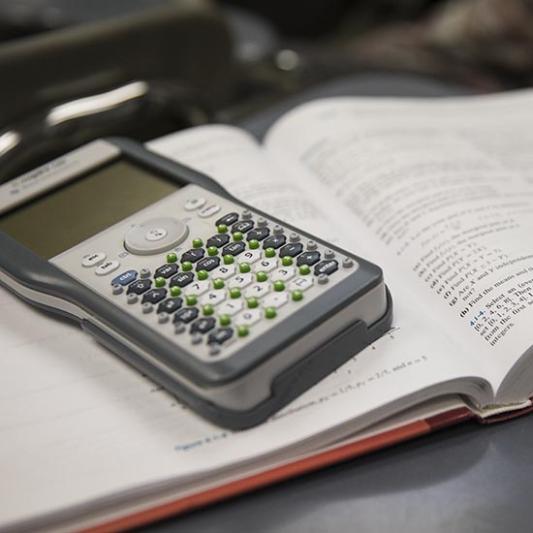 Calculator sits on top of a mathematics textbook.