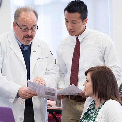 Pharmacy students work with a professor in class.