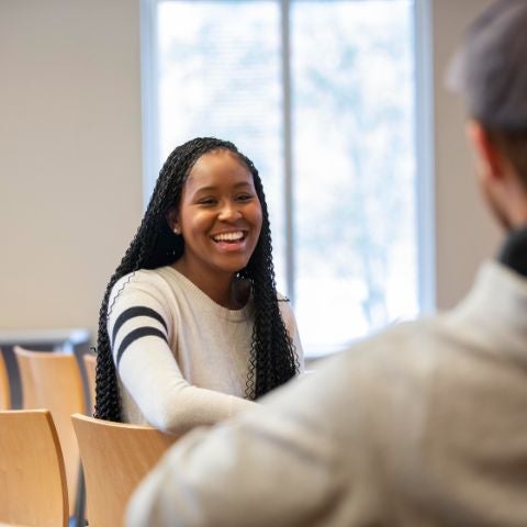 Alexis smiling and talking with a professor and student in the chapel