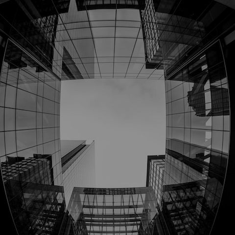 Looking up through tall buildings from the ground.