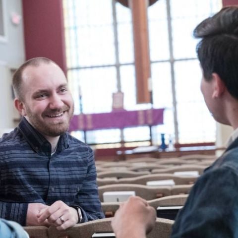 Students sitting together and talking in a church pew