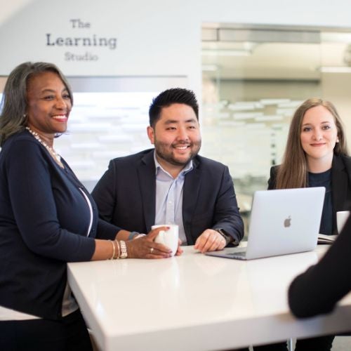 Business students talking and smiling around a desk