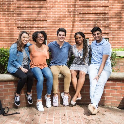 students sitting outside and smiling at the camera
