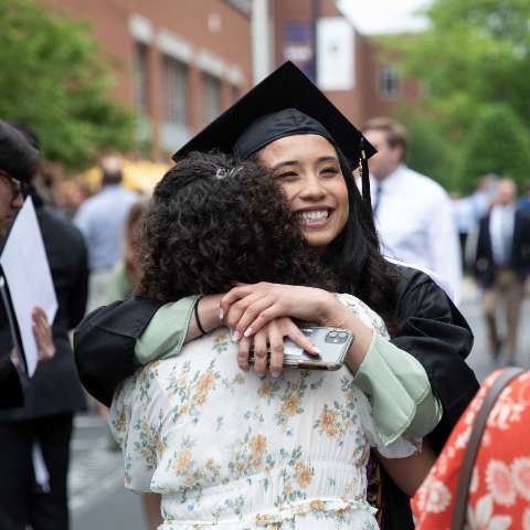 student smiling and hugging her mom after graduation