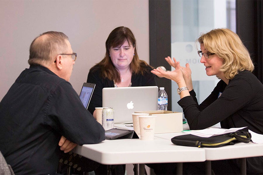 three people sitting at a table talking