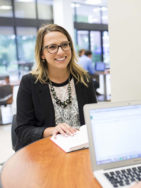 woman smiling at table with computers