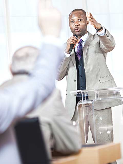 Man stands taking questions from audience members.