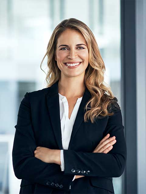 Woman standing against glass wall in professional attire.