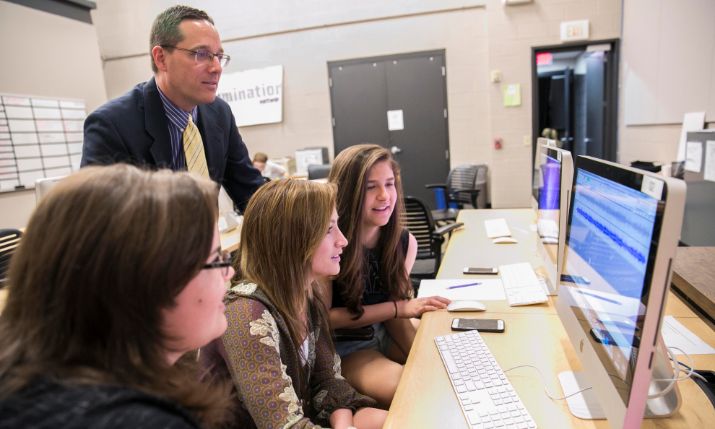 Teacher working with students in computer lab.