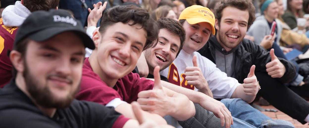 Students in a social club give the thumbs up signal while sitting together