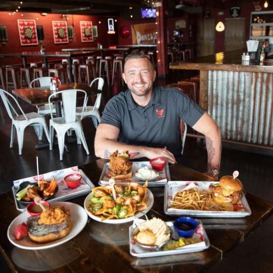 Austin Smith (’06) photo in front of Party Fowl menu items