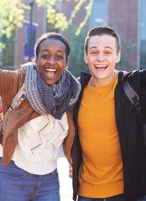 Two students with their hands up and smiling excitedly