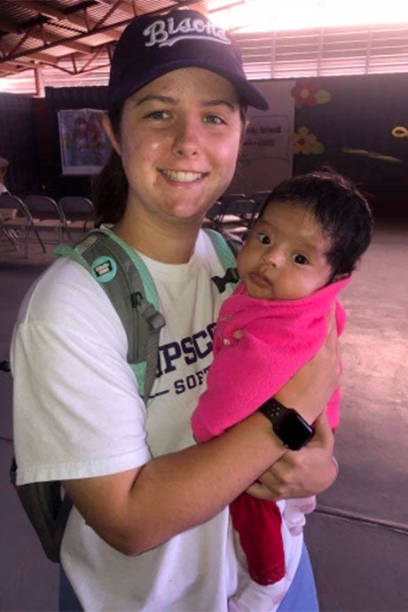 Softball student holds a infant on a mission trip to Baja, Mexico