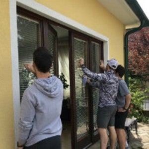 Students working on curtains at a house. 