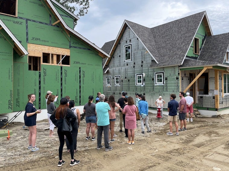 Students look on as they learn about the unfinished houses in the background