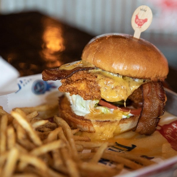 Party Fowl sandwich with oozing cheese sauce and bacon with a side of fries