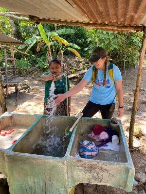A Guatemalan resident tries out their water tap for the first time with a Lipscomb student