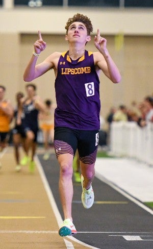 A track and field student athlete points up to his Higher power as he finishes a race