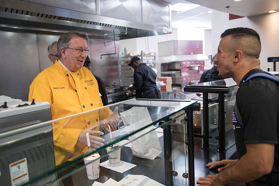 Lipscomb University President L. Randolph Lowry surprises students by serving them during the opening of Creekstone Burger Co.