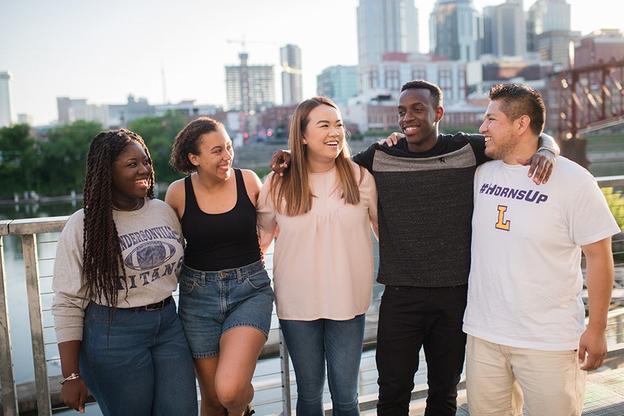 A diverse group of five Lipscomb students hanging out in Nashville in front of the skyline.