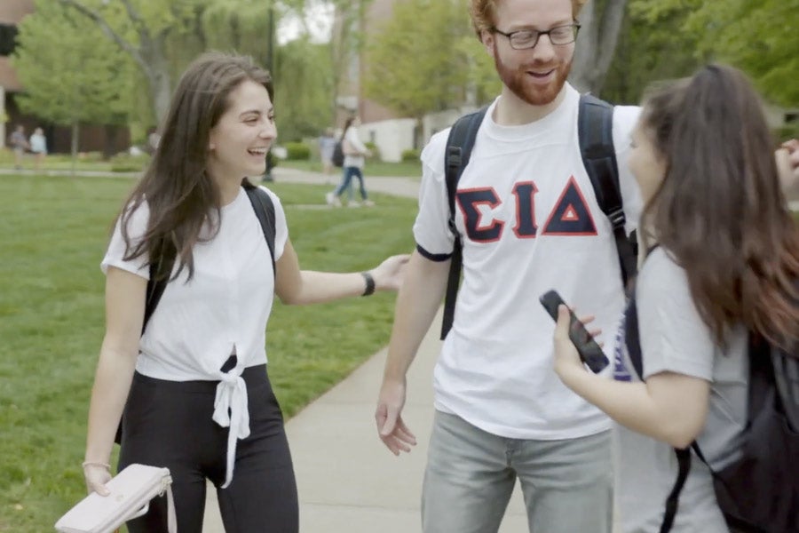 Students greet each other on the sidewalk