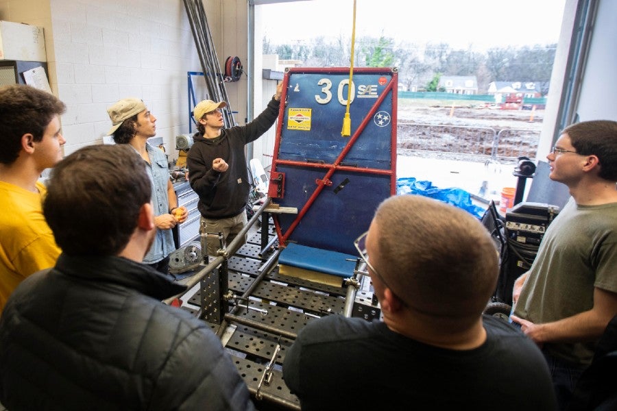 The Baja team looks over the frame of the ATV.