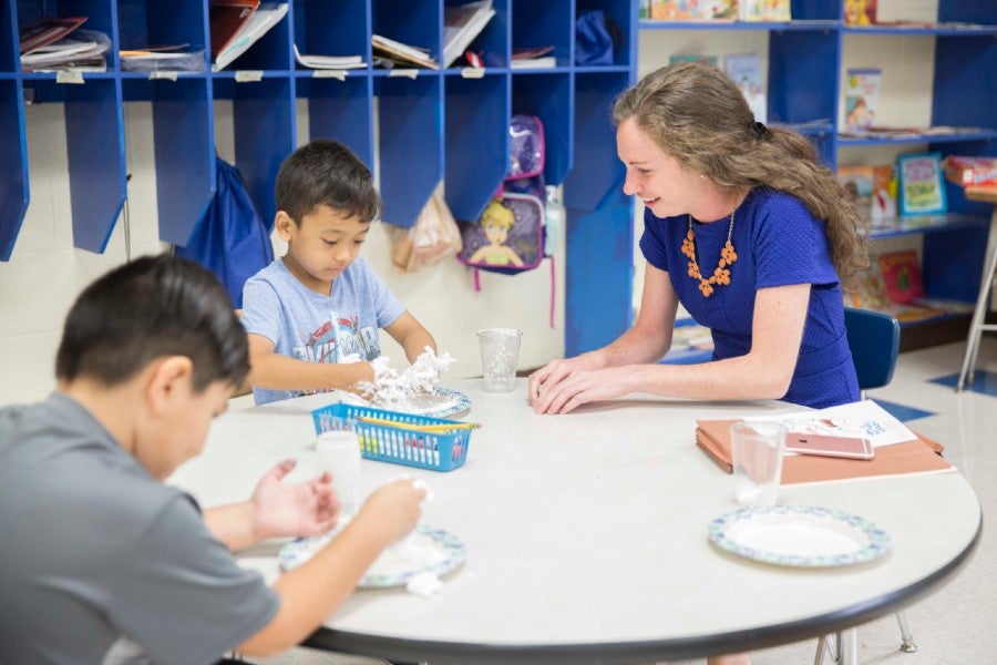 A teacher helping public school students in a group activity