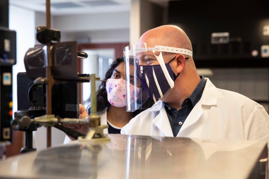 Professor working with student in face shield