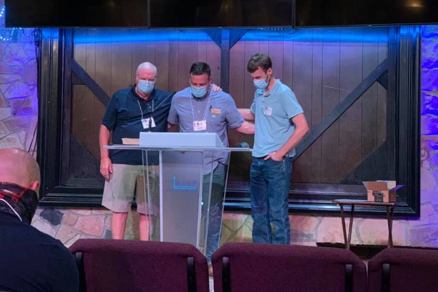 Three men praying on stage