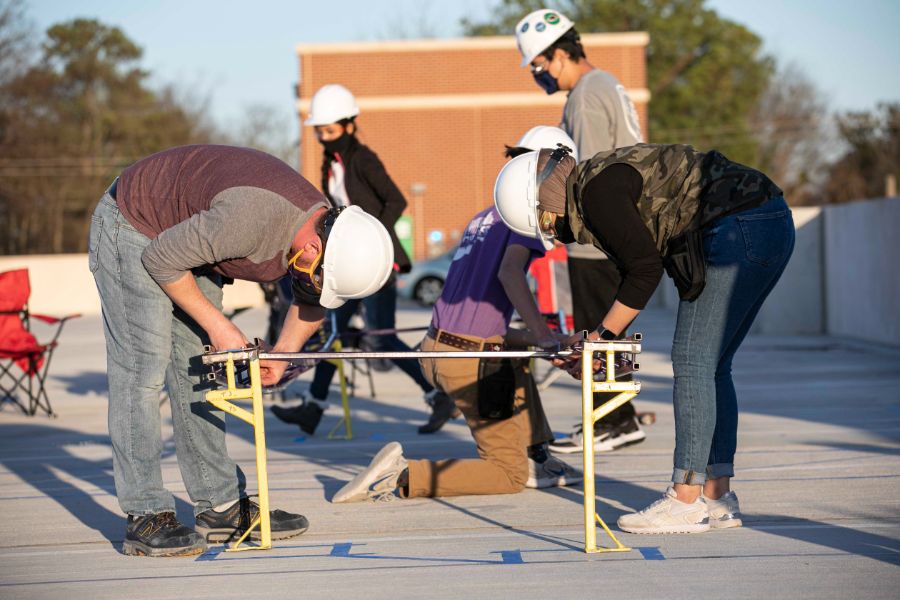 Two students building part of the bridge outdoors