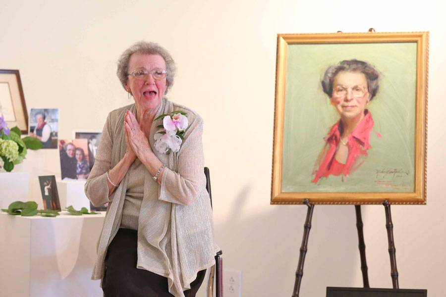 Mary Nelle Chumley sitting next to portrait of herself painted by Michael Shane Neal.