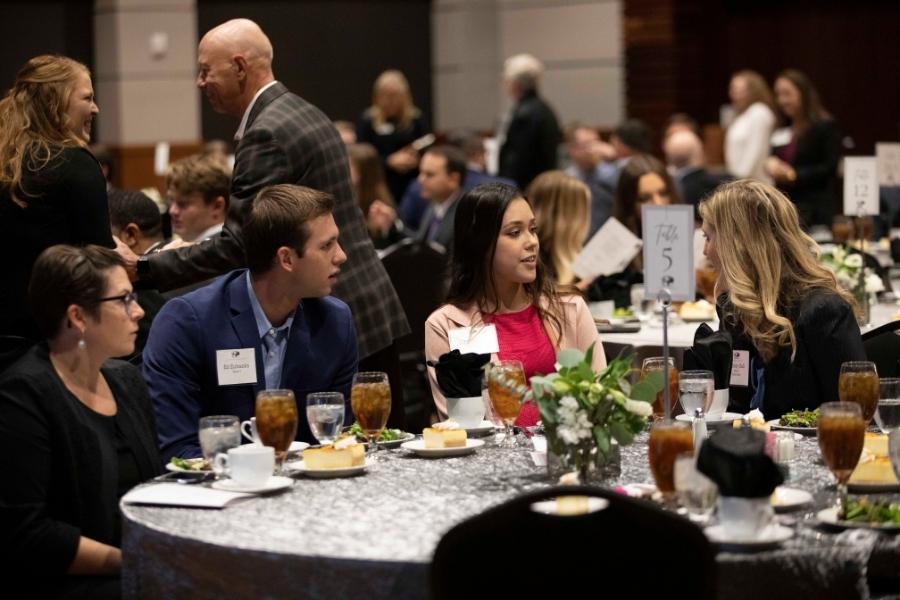 students engaging in table discussions at dinner