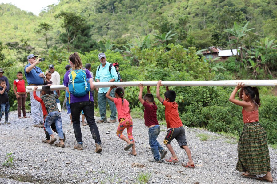 Children of the village helping haul pipe