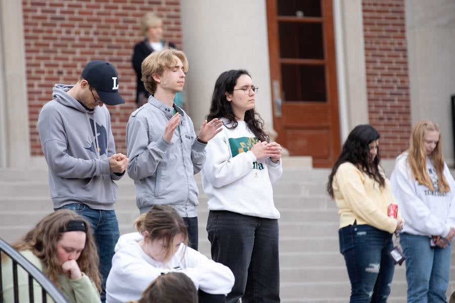 Students worshipping during devotional on the steps of Collins