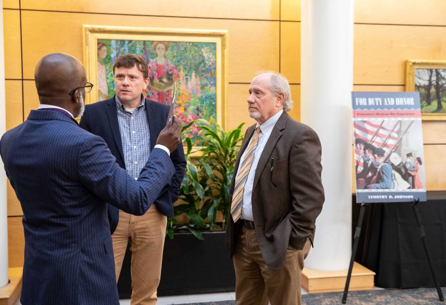 David Holmes, dean of the College of Liberal Arts & Sciences, talks with authors and professors Willie Steele, left, and Tim Johnson, right, at the authors showcase