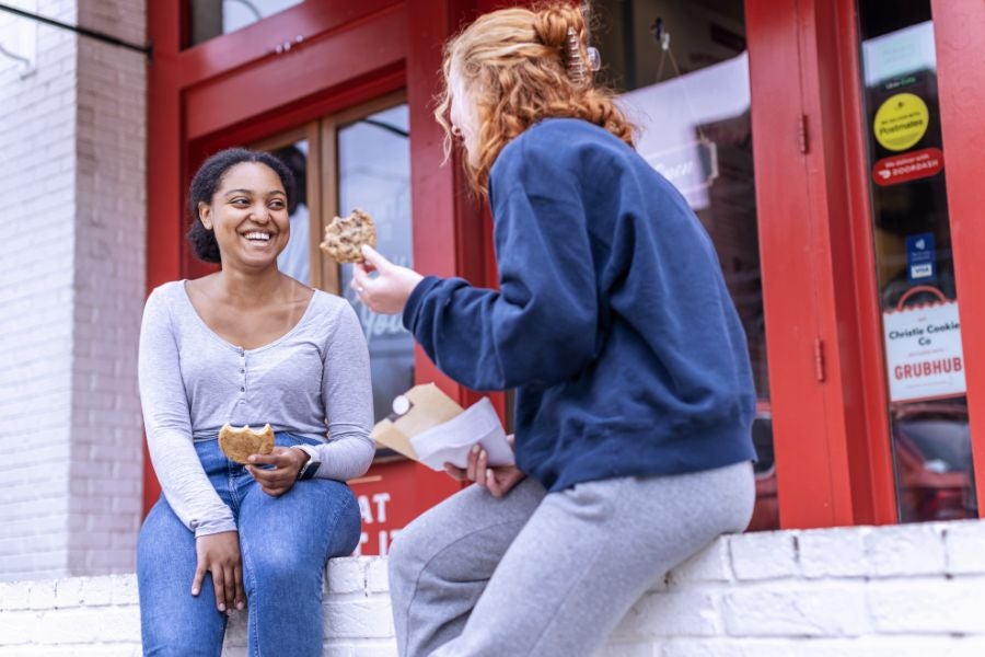 Two students eating cookies from Christie Cookie Co