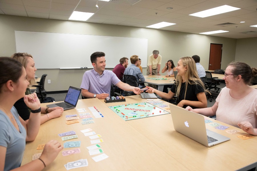 Alumnus Justin Cook plays Monopoly with students.