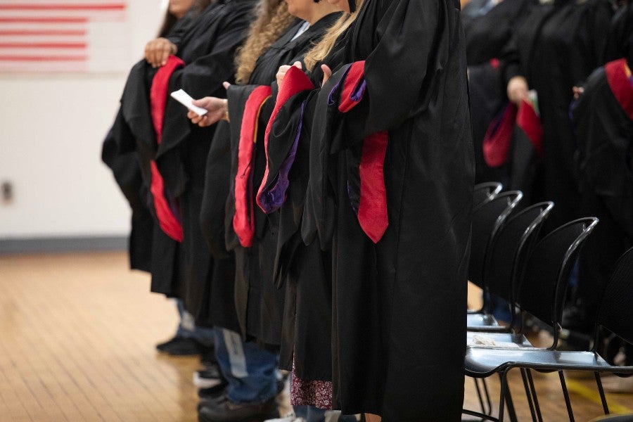 The graduates in their graduation regalia holding their hoods