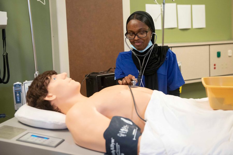 Student practices using stethoscope on medical dummy