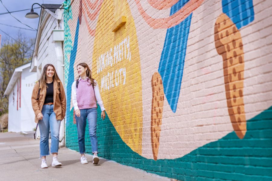 Students walking past a mural in the 12 south neighborhood
