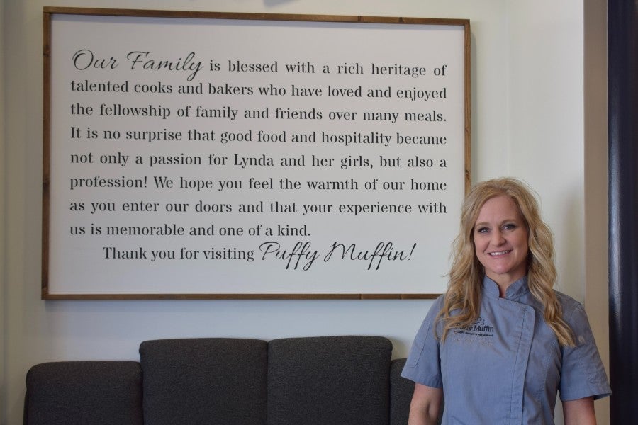 Kristi Stone standing beside restaurant's sign that describes the family restaurant.